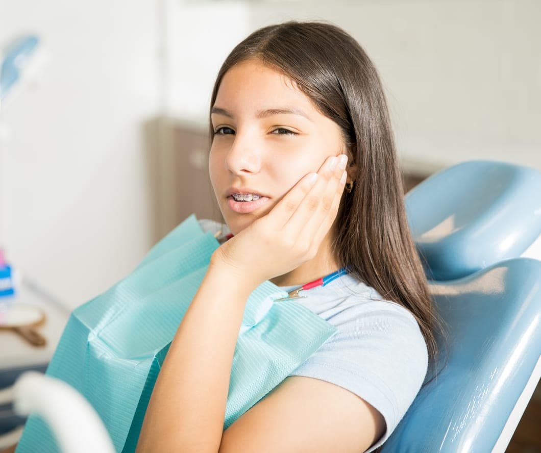 Teen patient holding her cheek in the dental chair